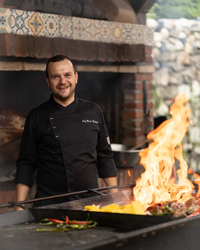 Outdoor branding photo of a chef in Sibiu grilling over open flames, combining traditional cooking methods with a strong visual atmosphere.