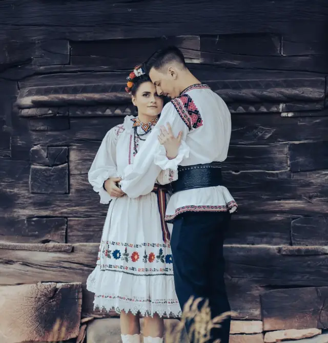 Trash the Dress photoshoot in Cluj-Napoca museum with couple in rustic Romanian outfits near traditional village houses.