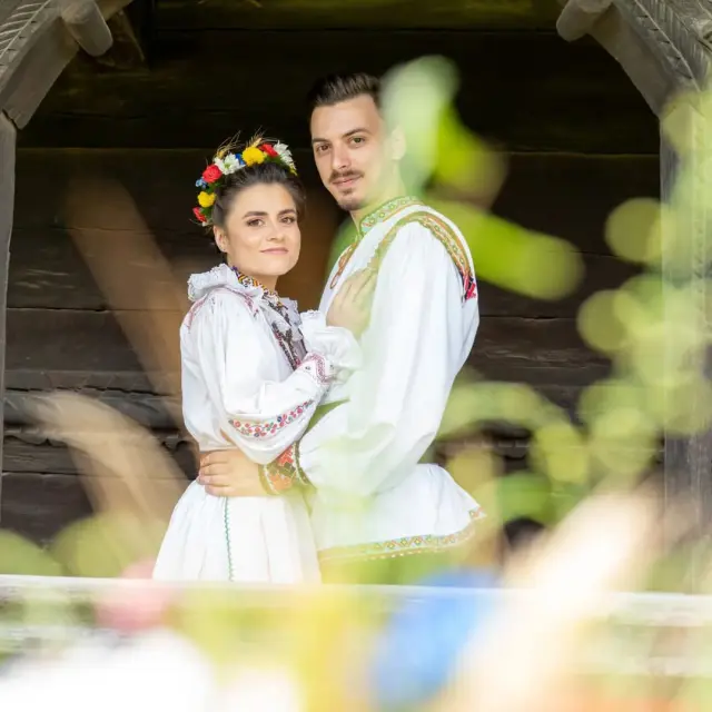 During their Trash the Dress photoshoot outdoors in Cluj-Napoca, the couple wears rustic Romanian costumes, surrounded by nature and traditional village houses.