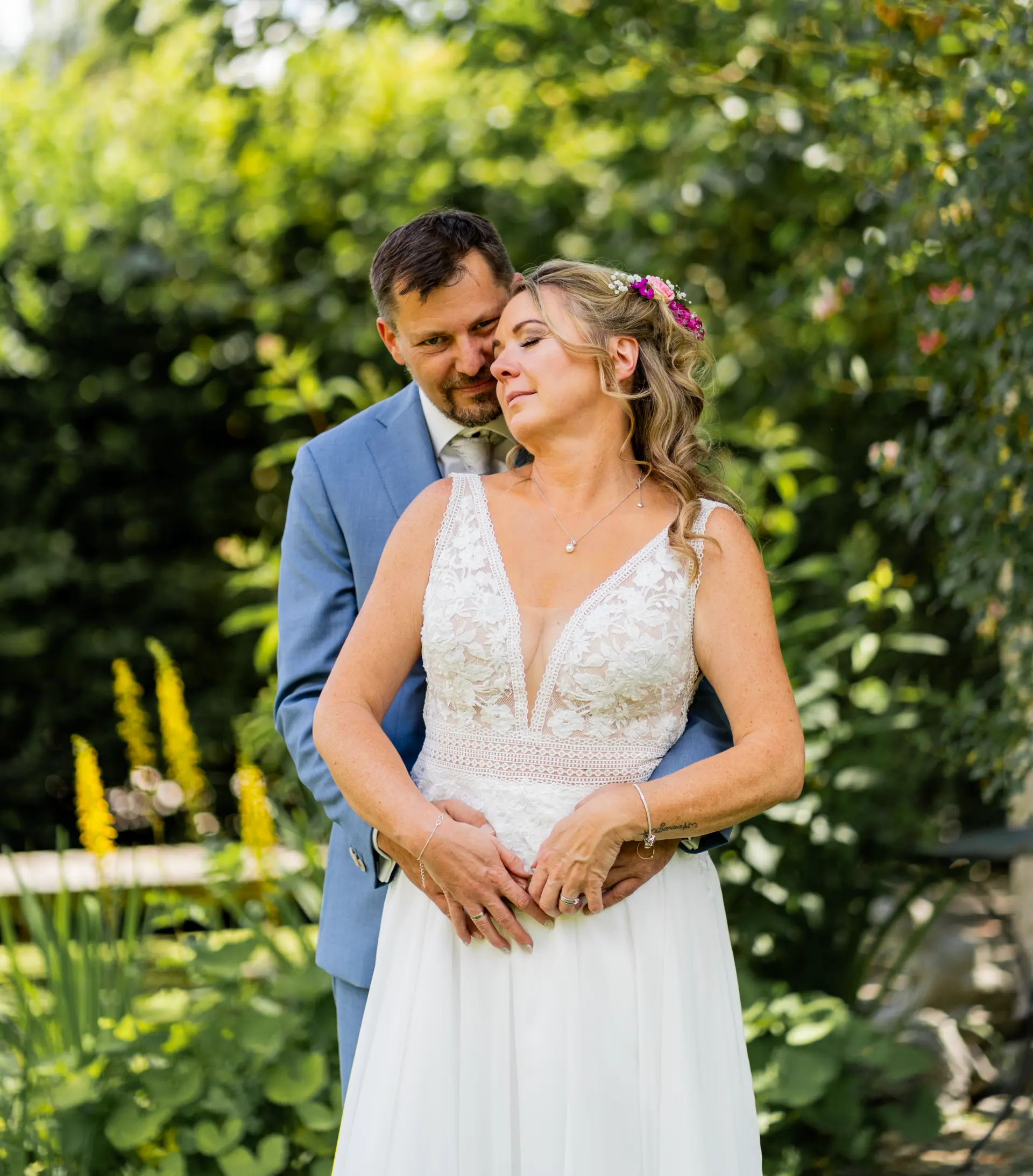 Porträt von Braut und Partner im Garten bei natürlichem Licht, das Liebe und Gelassenheit ausstrahlt.