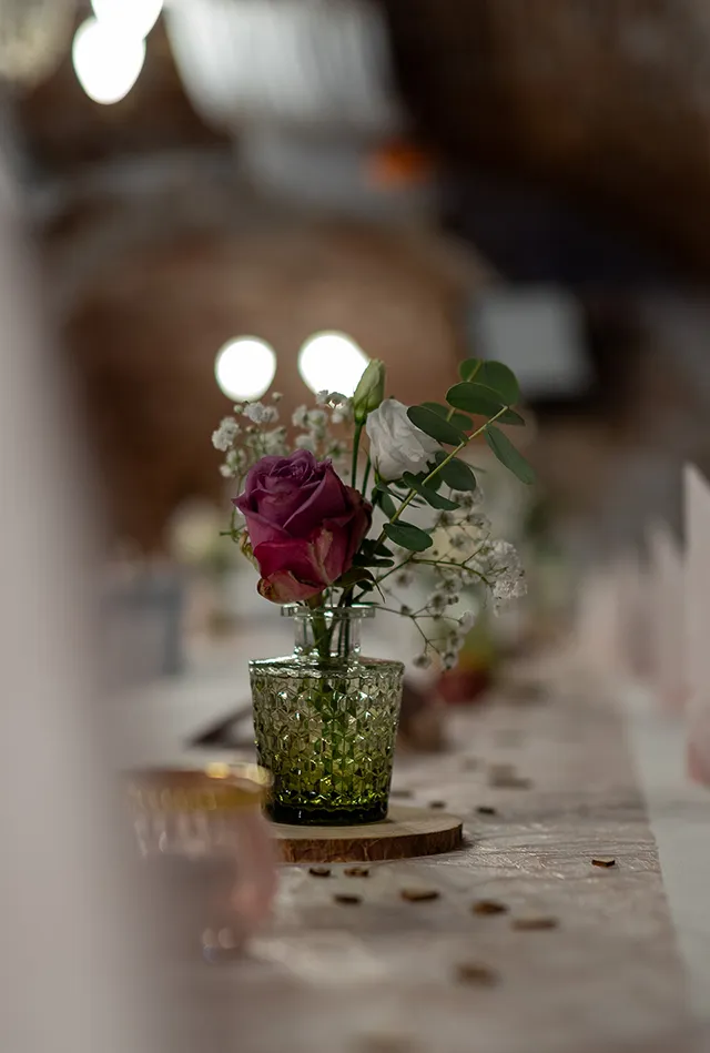 Wedding Photography in Landsberg – Close-up of wedding rings placed on a pink bouquet with white flowers and green leaves, set against a soft green-to-black gradient background.