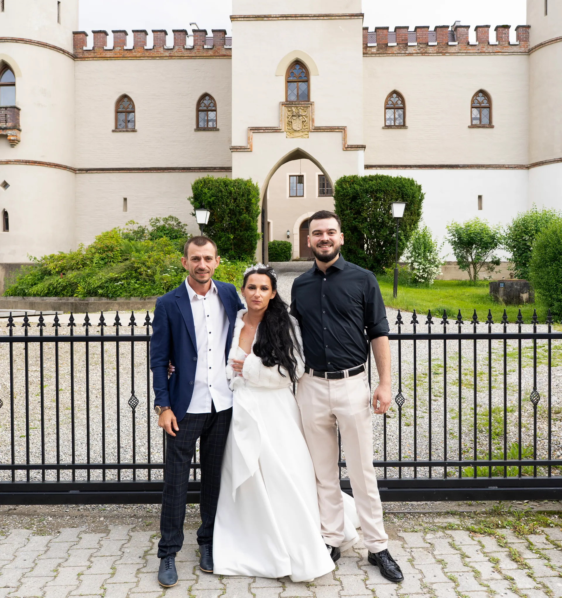 Bride and groom with a guest in front of the neo-Gothic Schloss Igling