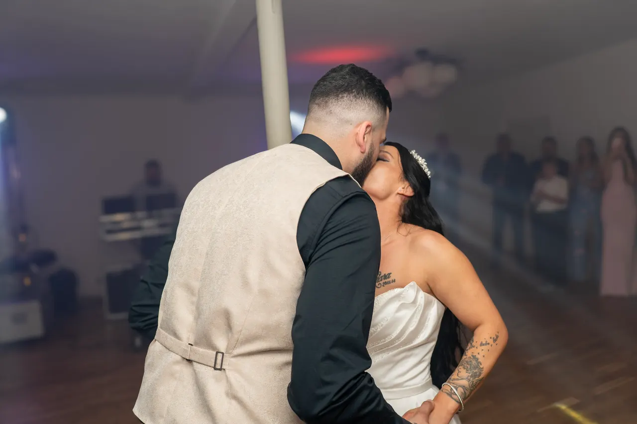 Bride and groom kissing while dancing in the reception hall