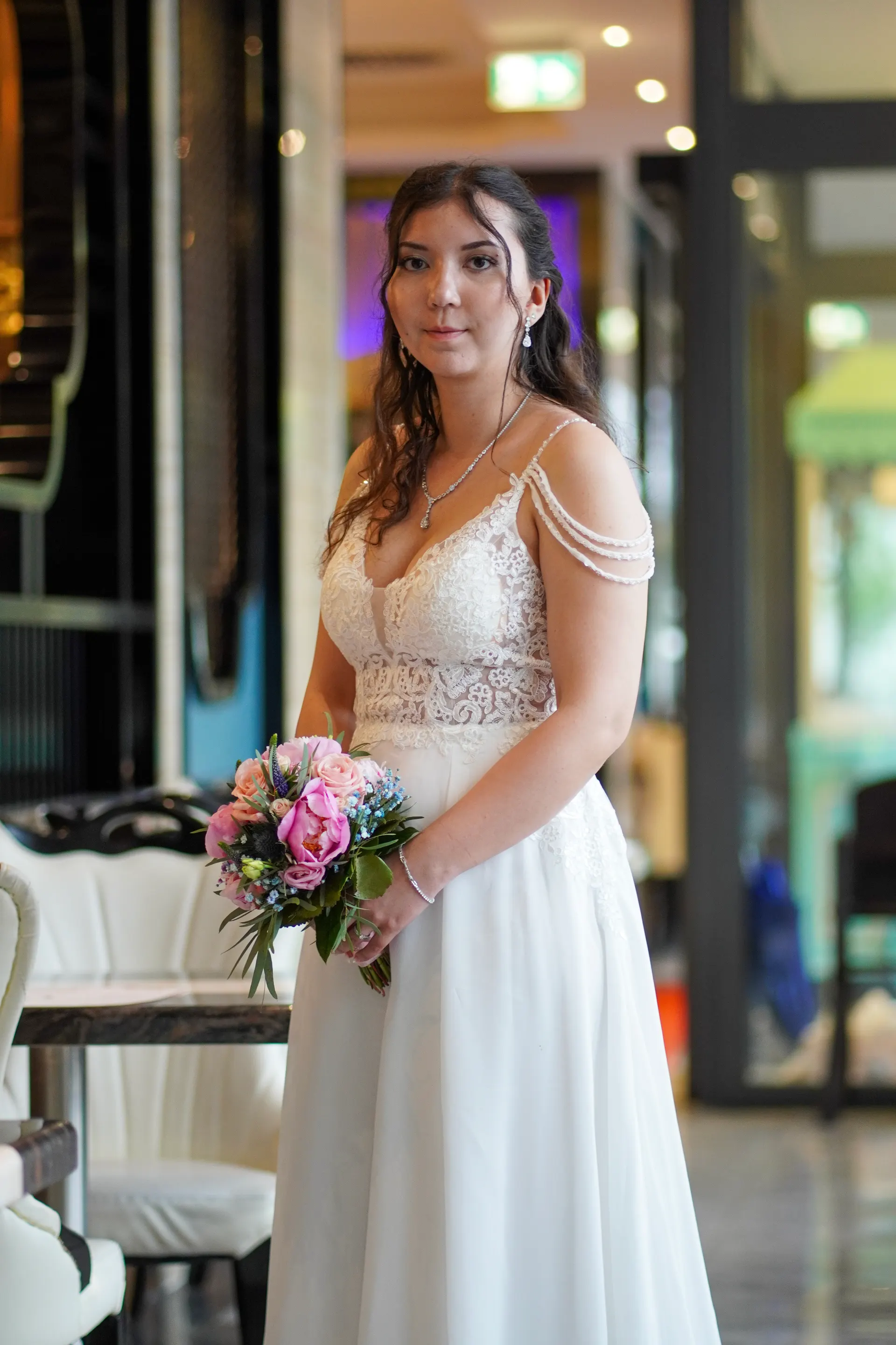 Bride in a white lace dress with her bouquet in the restaurant