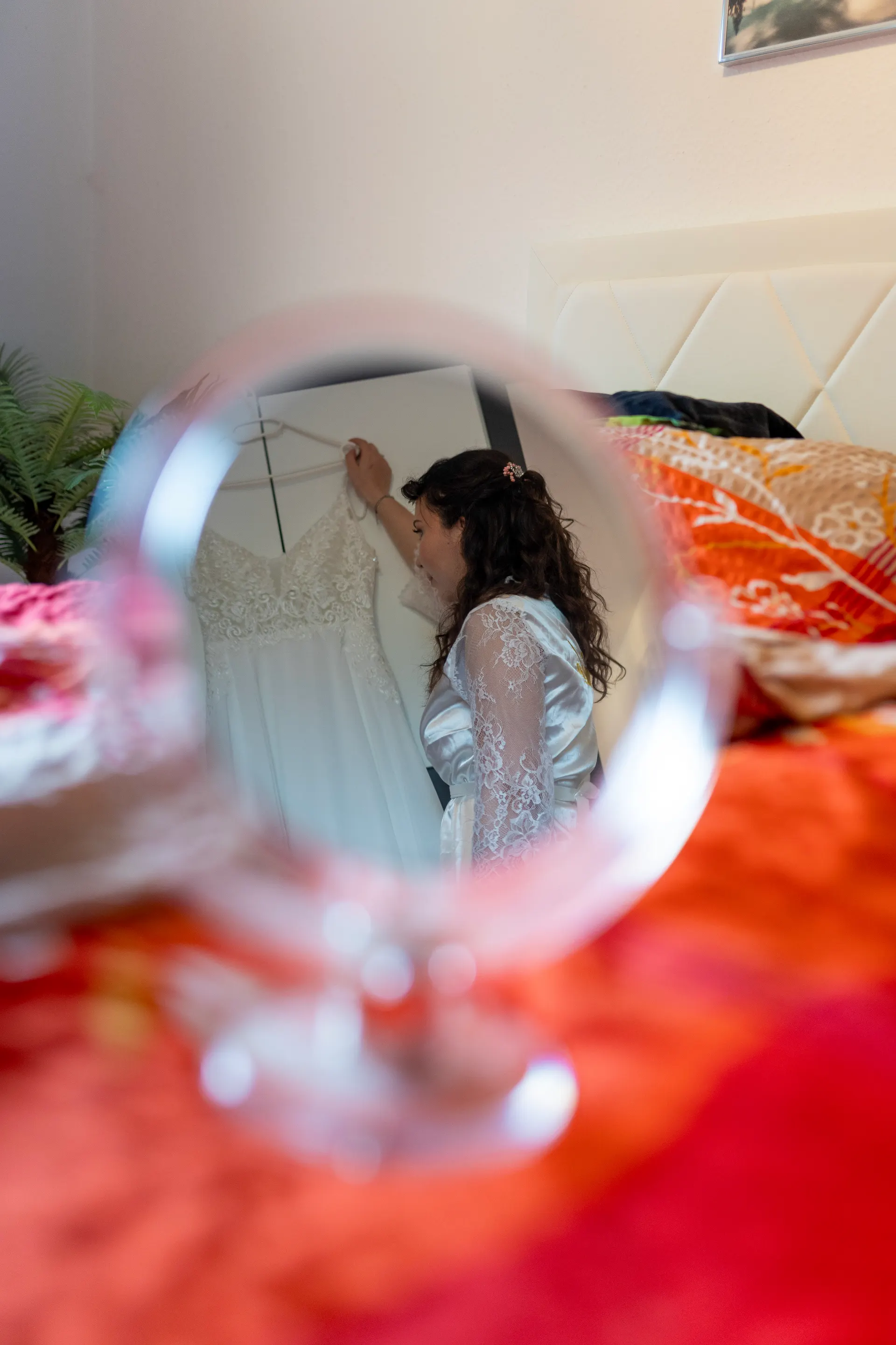 Wedding dress on a hanger, reflected in a small hand mirror