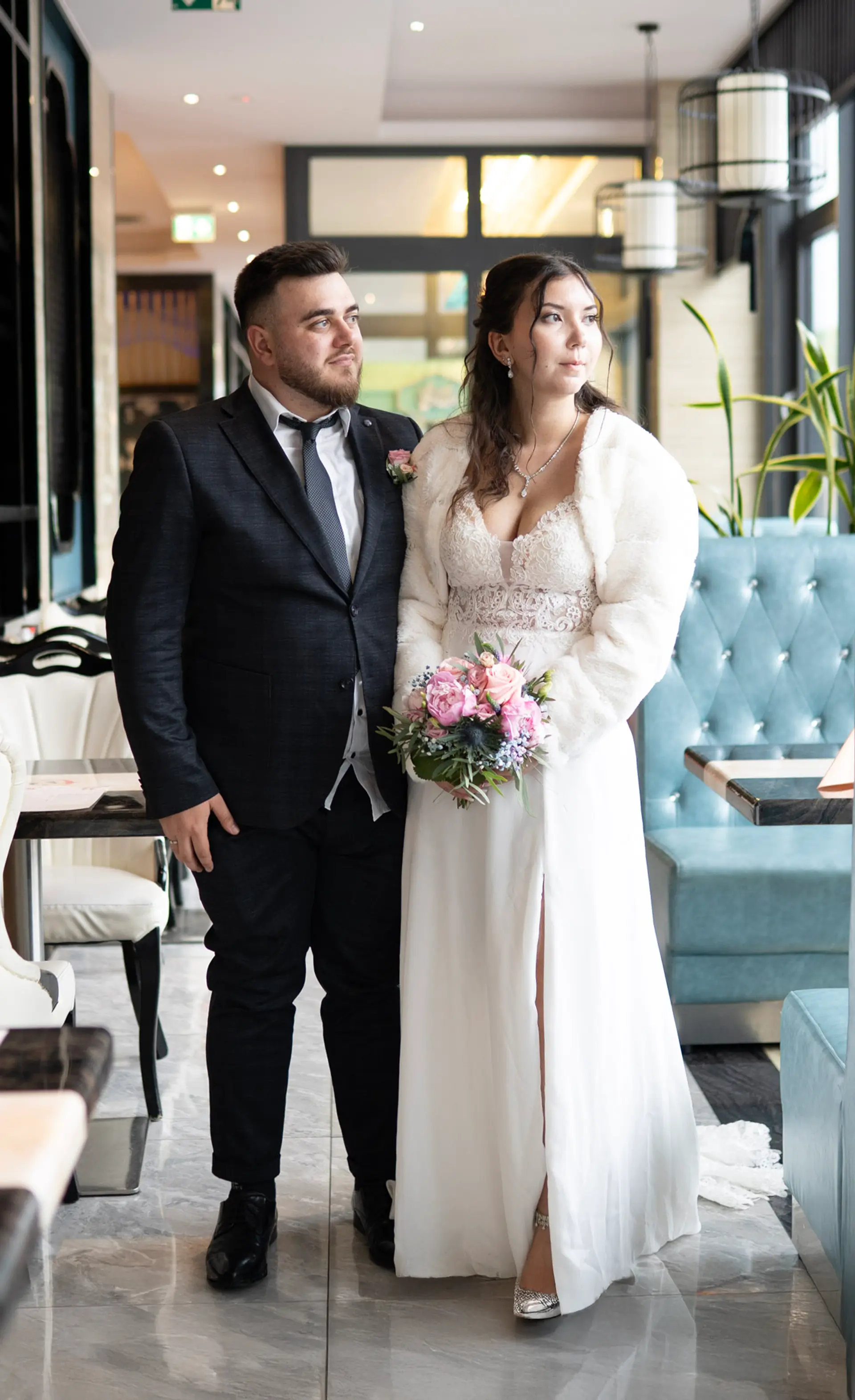 Bride and groom standing arm in arm in a restaurant, she holds the bouquet