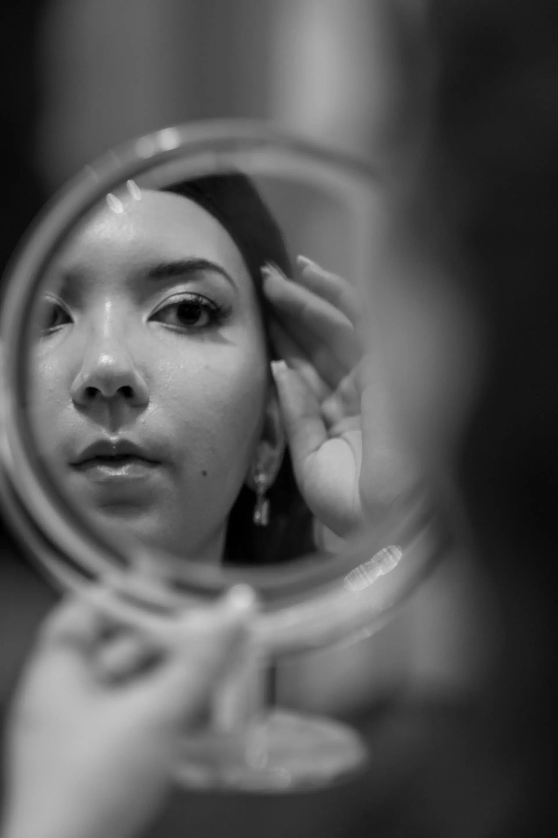 Bride looking at herself in a hand mirror, black and white portrait
