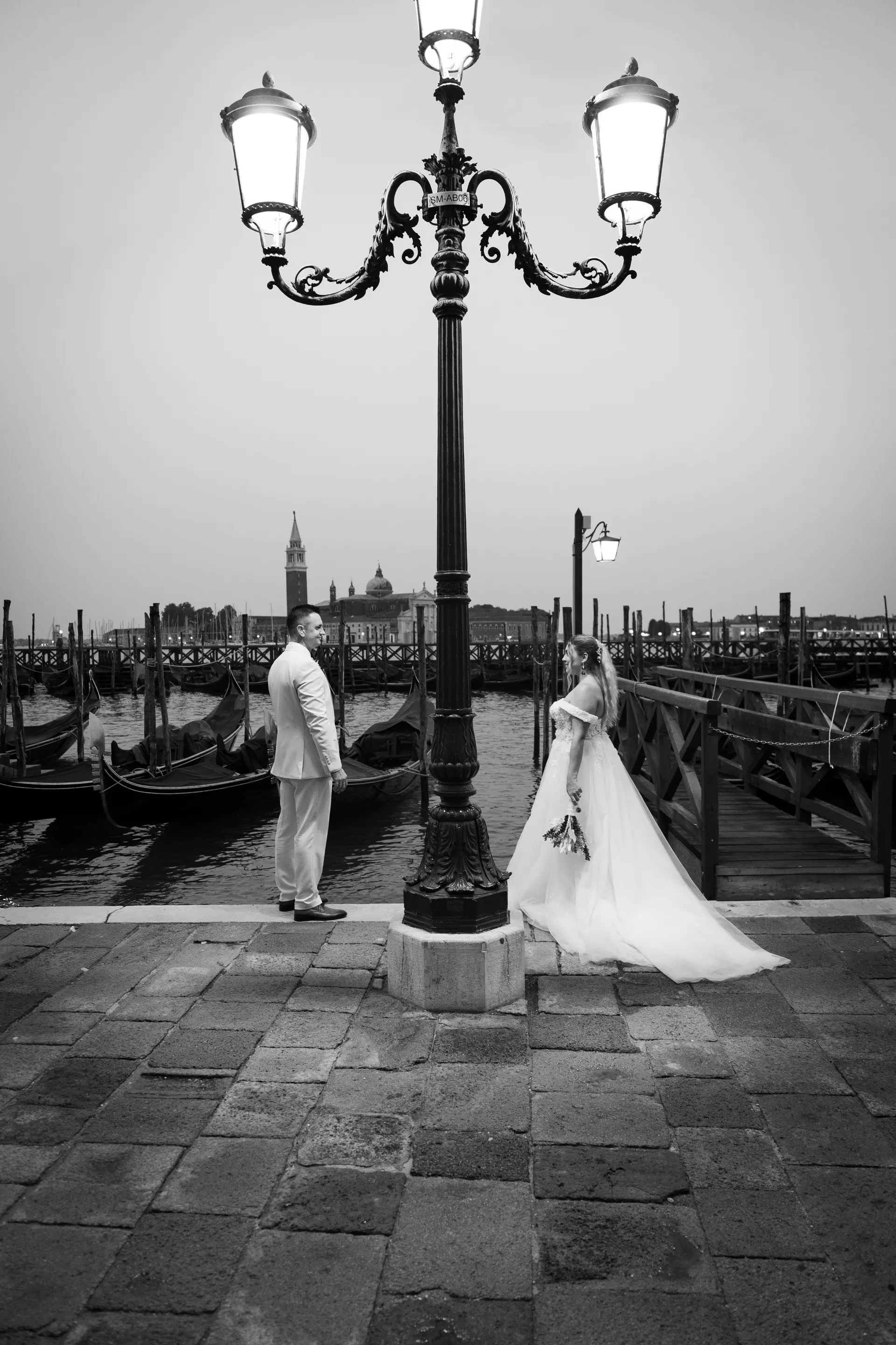 Bride and groom under a lantern in Venice, with gondolas and San Giorgio Maggiore behind